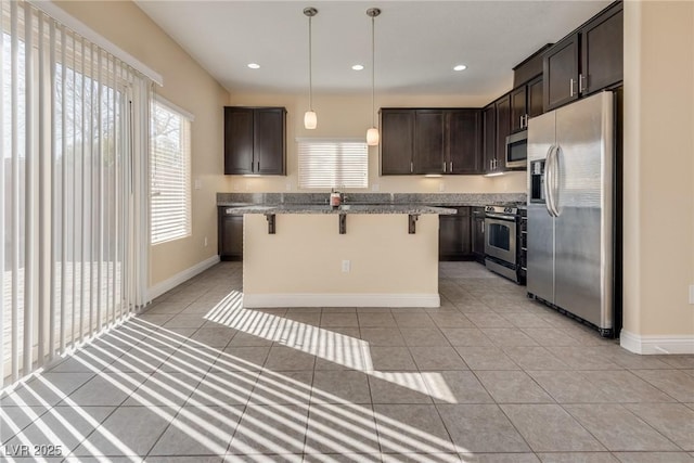 kitchen featuring light tile patterned flooring, a kitchen bar, a center island, appliances with stainless steel finishes, and pendant lighting