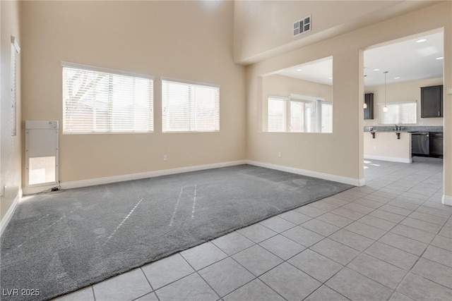 carpeted spare room featuring a towering ceiling