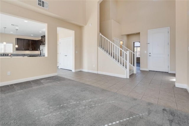 unfurnished living room featuring light tile patterned floors and a high ceiling