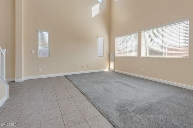 tiled spare room featuring a healthy amount of sunlight and a high ceiling