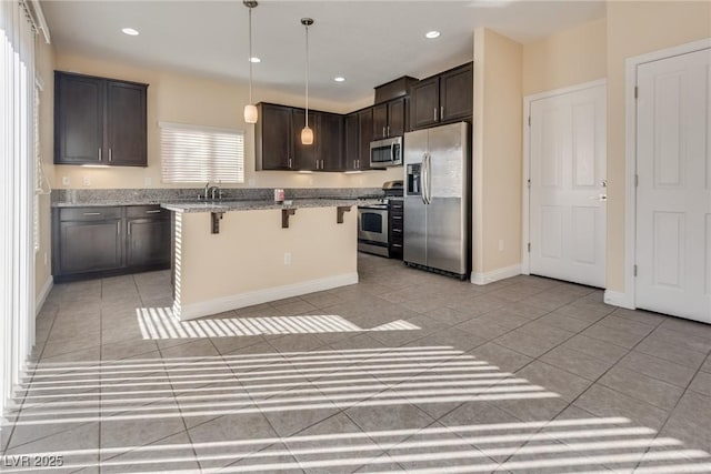 kitchen featuring dark brown cabinets, stainless steel appliances, a kitchen breakfast bar, a kitchen island, and decorative light fixtures