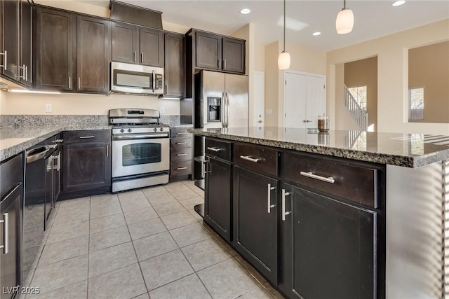 kitchen featuring appliances with stainless steel finishes, decorative light fixtures, dark stone counters, light tile patterned floors, and dark brown cabinetry