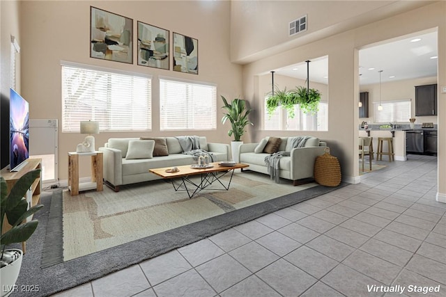 living room with a towering ceiling and light tile patterned floors