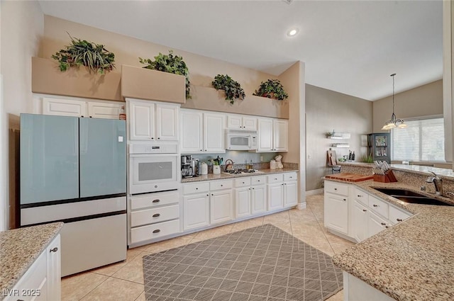 kitchen featuring light tile patterned flooring, pendant lighting, white cabinetry, sink, and white appliances