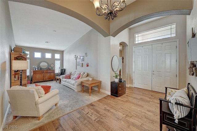 living room featuring a notable chandelier, a high ceiling, and light wood-type flooring