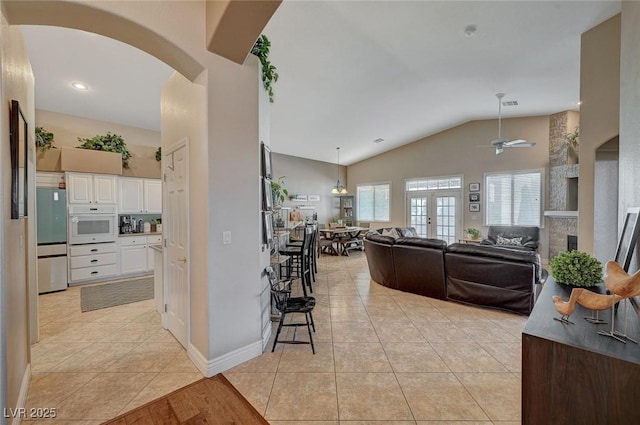 kitchen with white cabinetry, vaulted ceiling, light tile patterned floors, and oven