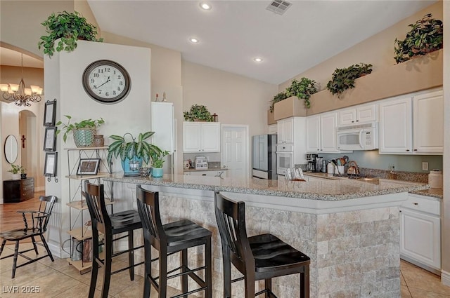 kitchen featuring white cabinetry, lofted ceiling, and white appliances