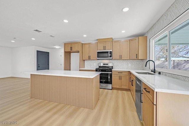 kitchen featuring sink, a kitchen island, light hardwood / wood-style floors, and appliances with stainless steel finishes