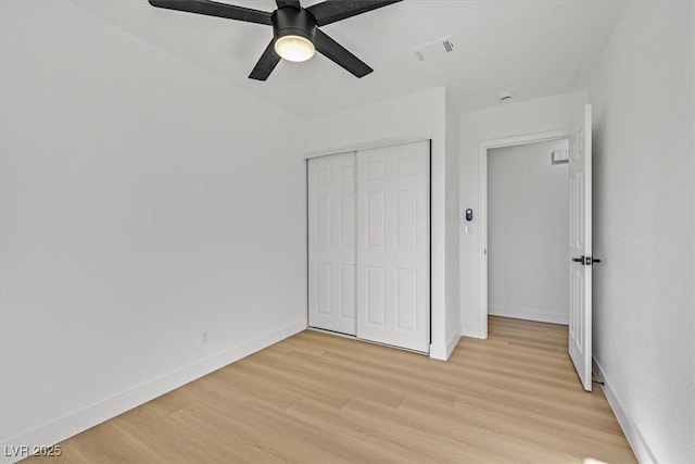 unfurnished bedroom featuring ceiling fan, light wood-type flooring, and a closet