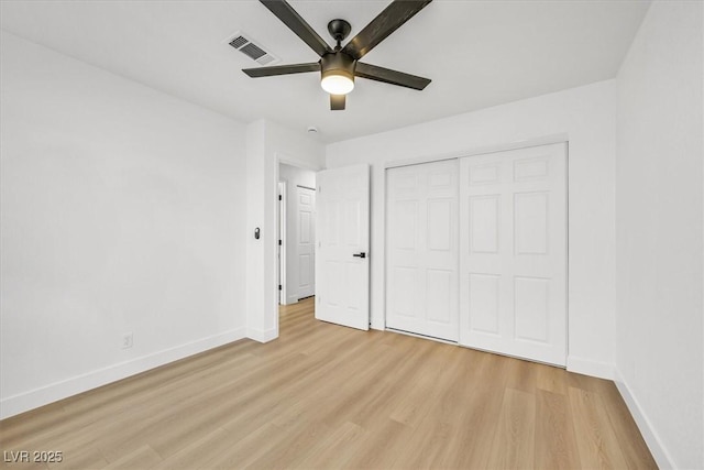 unfurnished bedroom with ceiling fan, light wood-type flooring, and a closet