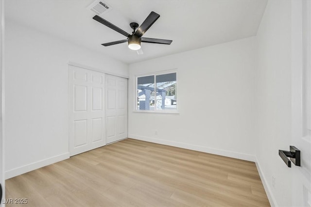 unfurnished bedroom featuring ceiling fan, a closet, and light wood-type flooring