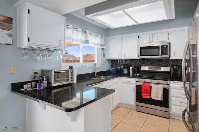 kitchen featuring white cabinetry, sink, dark stone counters, kitchen peninsula, and stainless steel appliances