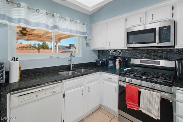 kitchen featuring sink, dark stone countertops, appliances with stainless steel finishes, white cabinets, and backsplash