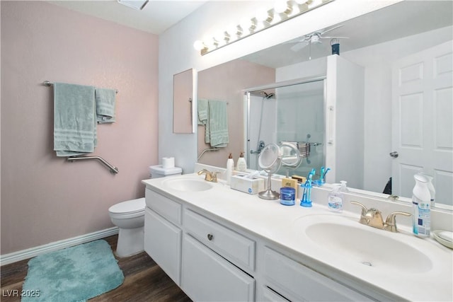 bathroom featuring ceiling fan, vanity, wood-type flooring, a shower with shower door, and toilet