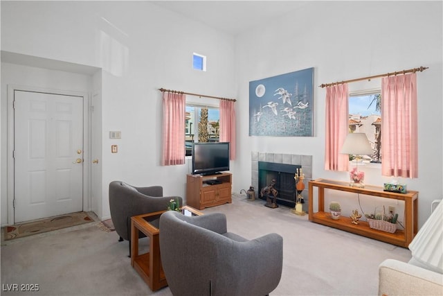 carpeted living room featuring a towering ceiling and a tiled fireplace