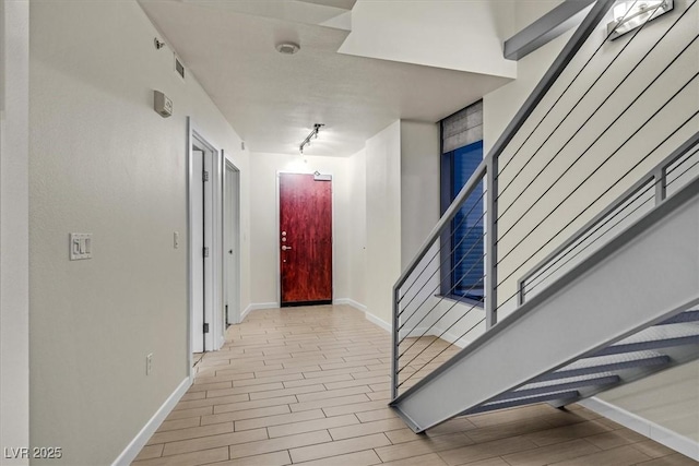 hall featuring visible vents, stairs, baseboards, and wood finish floors