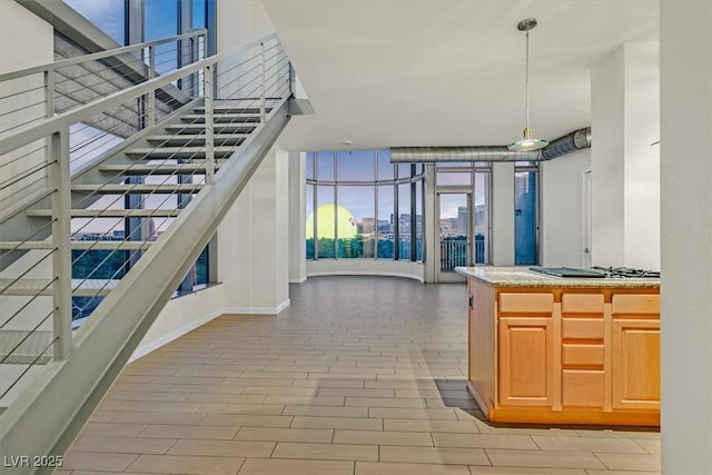 kitchen with a view of city, stainless steel gas cooktop, light countertops, hanging light fixtures, and wood tiled floor