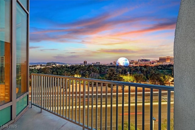 balcony at dusk featuring a view of city