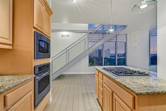 kitchen with a city view, decorative light fixtures, light wood finished floors, appliances with stainless steel finishes, and light stone countertops