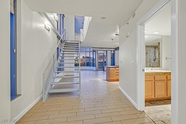 corridor with stairs, a sink, visible vents, and wood tiled floor