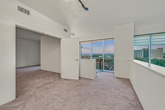 unfurnished room with light carpet, lofted ceiling, and visible vents