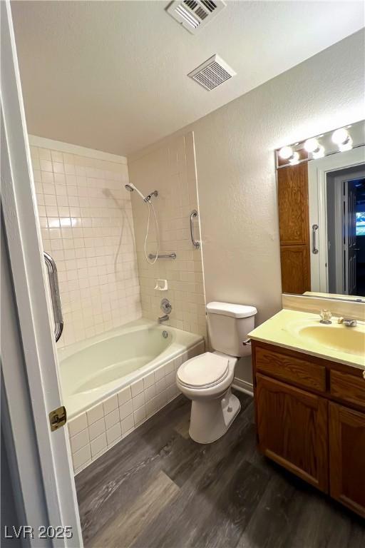 full bathroom with vanity, toilet, hardwood / wood-style floors, and tiled shower / bath