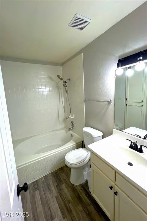 full bathroom with tiled shower / bath, vanity, toilet, and hardwood / wood-style floors