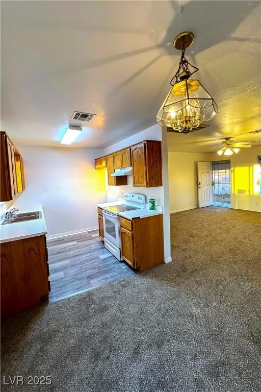 kitchen with dark carpet, sink, electric range, and decorative light fixtures