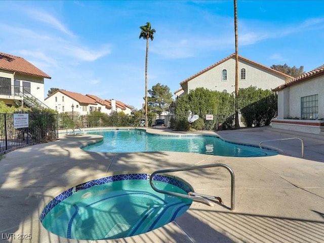 community pool with fence, a community hot tub, and a patio area