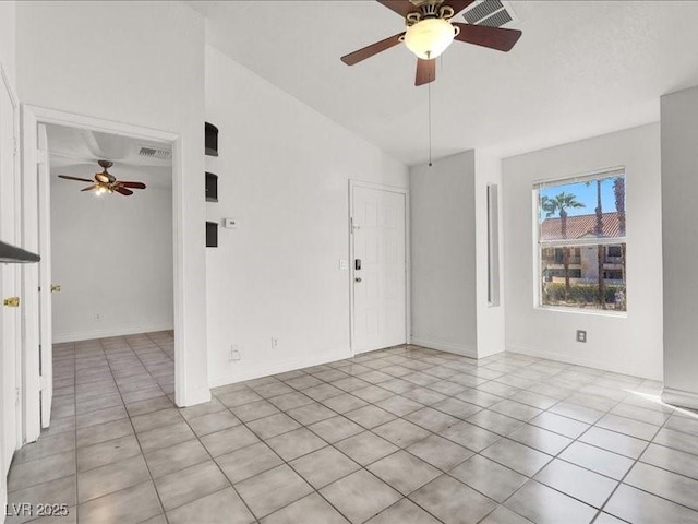 empty room featuring vaulted ceiling, visible vents, light tile patterned floors, and a ceiling fan