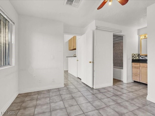 spare room featuring baseboards, light tile patterned floors, visible vents, and a ceiling fan