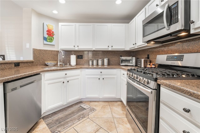 kitchen with appliances with stainless steel finishes, sink, and white cabinets