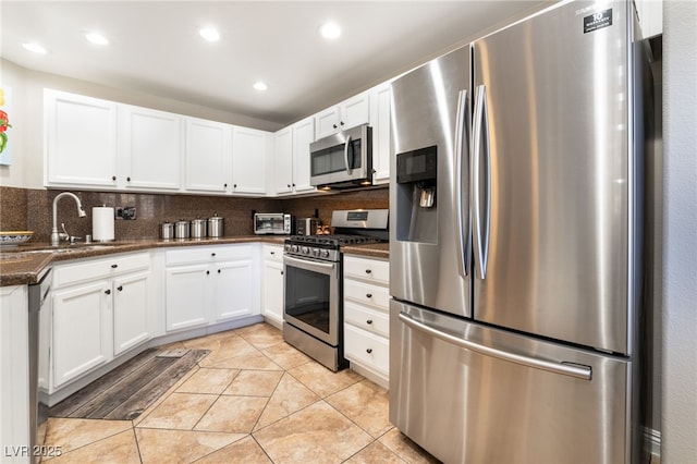 kitchen featuring backsplash, light tile patterned flooring, white cabinets, and appliances with stainless steel finishes