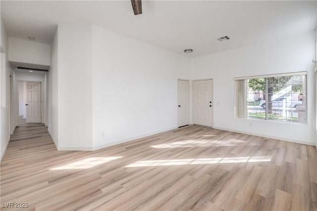 unfurnished room featuring light hardwood / wood-style floors and a high ceiling