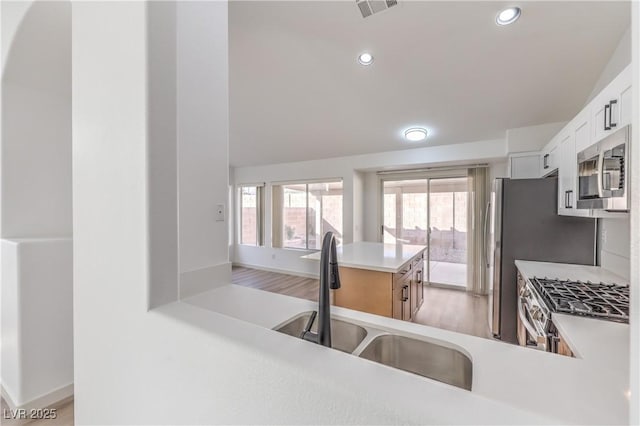 kitchen featuring sink, white cabinetry, light hardwood / wood-style flooring, appliances with stainless steel finishes, and kitchen peninsula