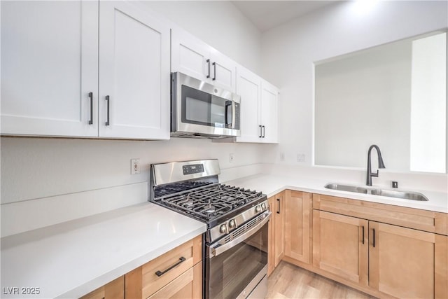 kitchen featuring sink, white cabinets, stainless steel appliances, light brown cabinets, and light hardwood / wood-style flooring