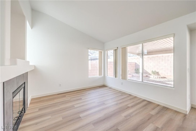 unfurnished living room with light hardwood / wood-style flooring, vaulted ceiling, and a tile fireplace