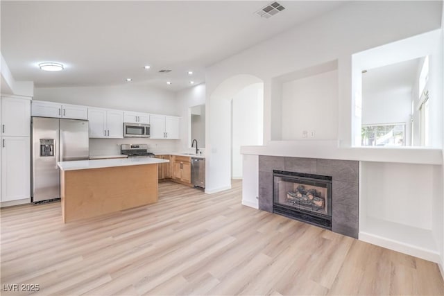 kitchen with white cabinetry, appliances with stainless steel finishes, sink, and a fireplace