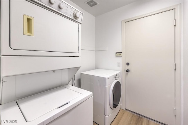 laundry area with stacked washer and clothes dryer and light wood-type flooring