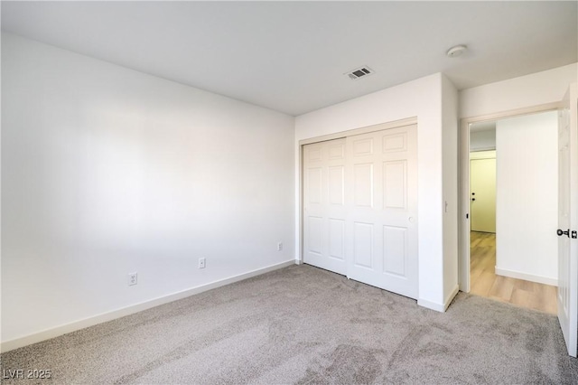 unfurnished bedroom with light colored carpet and a closet