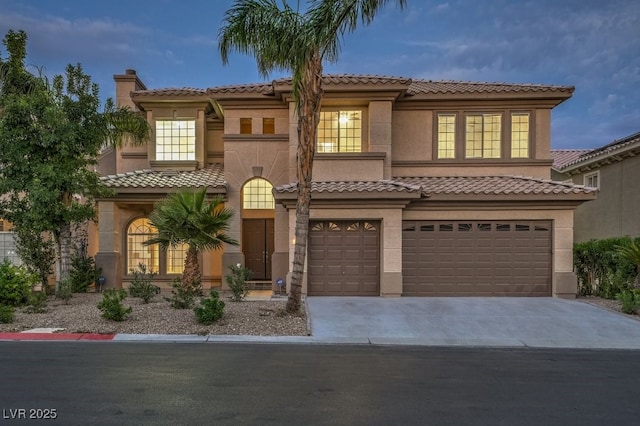 mediterranean / spanish-style home with driveway, stucco siding, an attached garage, and a tile roof