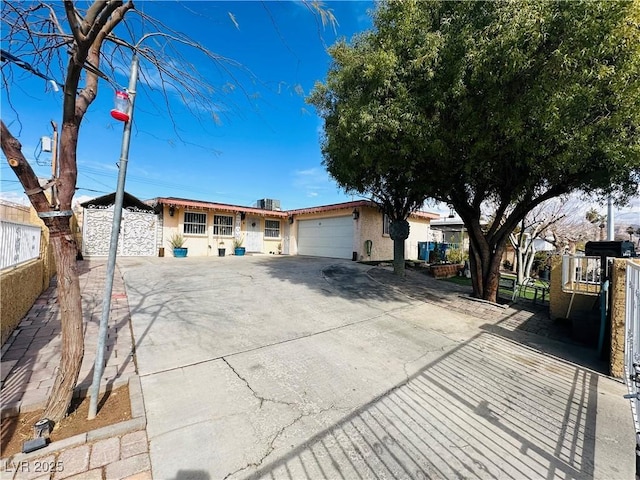 single story home with concrete driveway, fence, an attached garage, and stucco siding