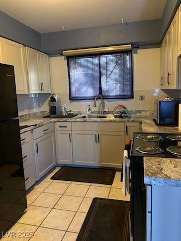 kitchen with sink, tasteful backsplash, black appliances, white cabinets, and light tile patterned flooring