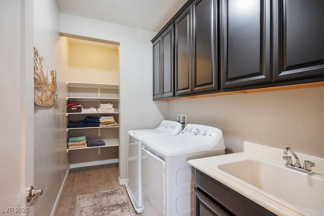 laundry room featuring independent washer and dryer, cabinets, wood-type flooring, and sink