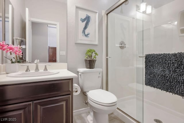 bathroom featuring a shower with door, vanity, and toilet