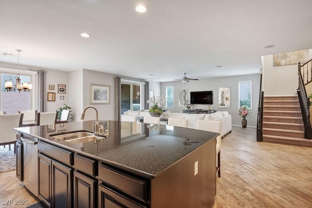 kitchen featuring sink, stainless steel dishwasher, a kitchen island with sink, pendant lighting, and ceiling fan with notable chandelier