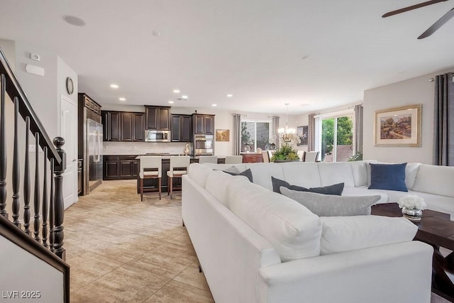 living room featuring ceiling fan with notable chandelier