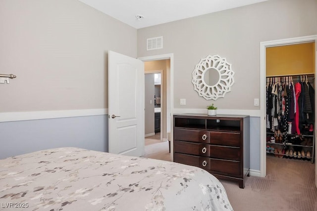 bedroom with a walk in closet, light colored carpet, and a closet