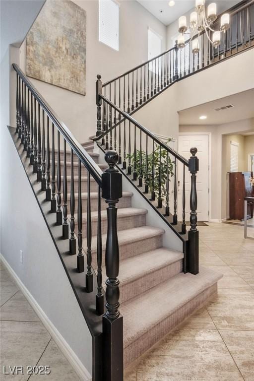 stairs with a notable chandelier and a high ceiling