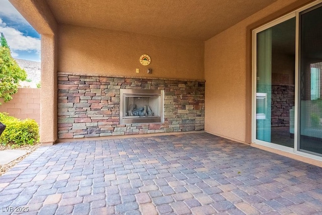 view of patio / terrace with fence and an outdoor stone fireplace